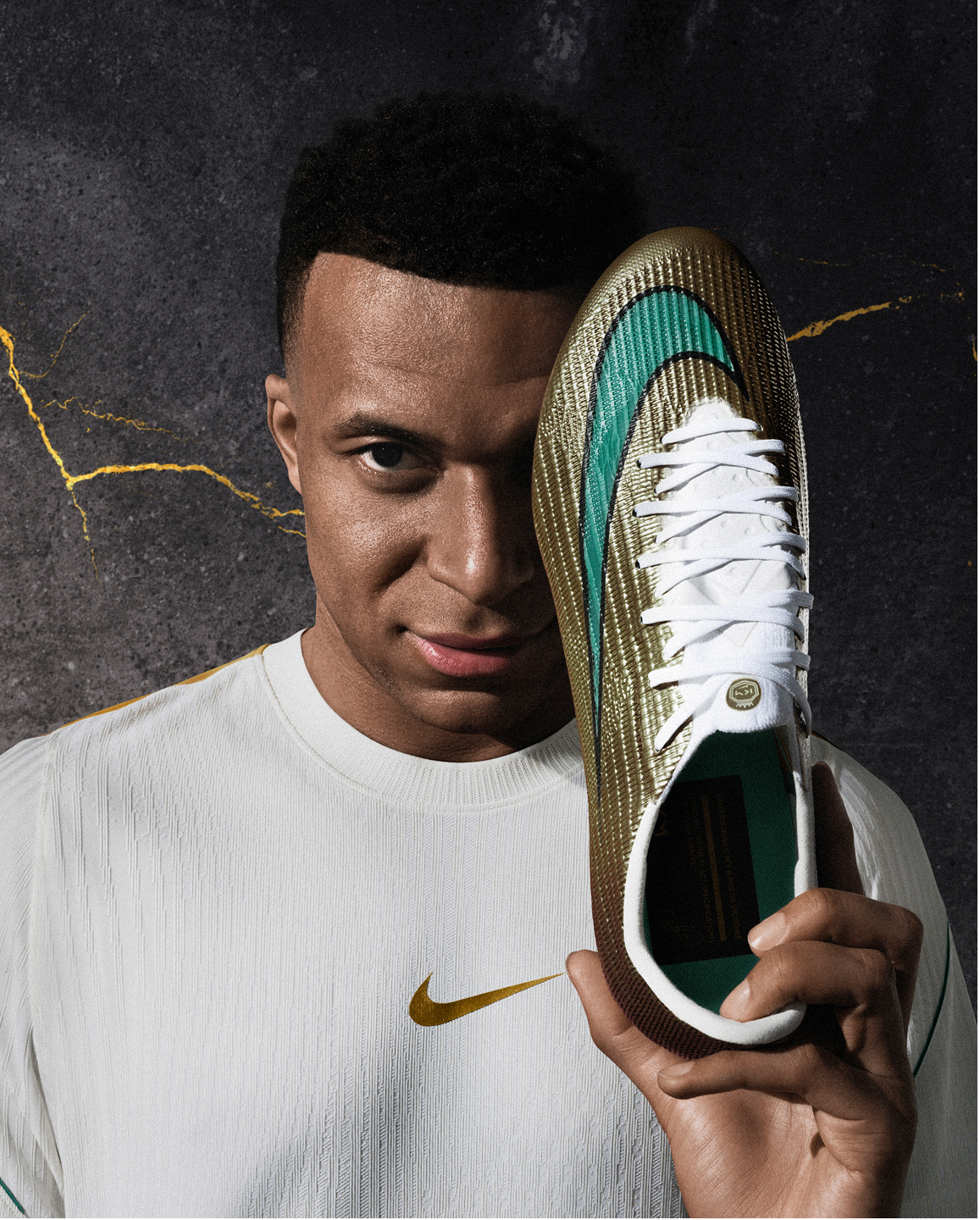 Portrait of Kylian Mbappé holding the football boot covering his left eye.